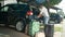 LENS FLARE: Young man picking up the last travel bag out of the trunk of his car