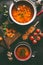 Lentil soup in pot and bowl with spoon and ladle. Cooking ingredients on dark rustic kitchen table background, top view. Healthy