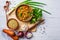 Lentil soup in a wooden bowl and ingredients on a white wooden b