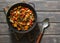 Lentils and seasonal garden vegetables braised in the pan on wooden background, top view.