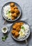 Lentils vegetarian roasted meatballs with curry sauce and rice - healthy lunch on grey background, top view.