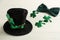 Leprechaun hat, bow tie and decorative clover leaves on white wooden table, space for text. St Patrick`s Day celebration