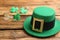 Leprechaun hat, decorative clover leaves and coins on wooden background, space for text. St Patrick`s Day celebration