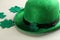 Leprechaun hat and decorative clover leaves on white wooden table, closeup. St Patrick`s Day celebration