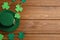 Leprechaun hat and decorative clover leaves on wooden table, flat lay with space for text. St Patrick`s Day celebration