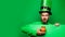 Leprechaun man in green hat and hoodie holding pot of gold. Bearded man wearing leprechaun costume isolated at green