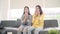 Lesbian Asian couple watching TV laugh in living room at home, sweet couple enjoy funny moment.