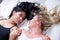 lesbians lovers in bed at morning, blonde and brunet girls holding their hands, in a white background