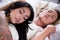 lesbians lovers in bed at morning, brunette girl is sleeping over the blonde girl chest, in a white background