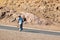 Lesotho, adult smiling african shepherd man in national wool blanket dress and hat walking on rural high mountains, Drakensberg