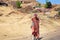 Lesotho, young african shepherd man in national red wool blanket dress and balaclava cap on rural high mountain road in village