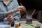 A lesson in long cozy winter evenings - a girl sits at a table and dips a brush in a glass to clean it from pigment, in her other