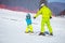 Lesson at skiing school: instructor teaching little skier