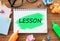 LESSON word written on notepad on wooden table with glasses, colorful markers and stickers for notes