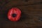 Lest We Forget, Red Poppy Lapel Pin Badge on dark recycled wood with copy space.