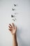 Let go and let fly. Studio shot of a unrecognizable persons hand releasing butterflies into the air on a grey background