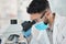 Let me take a look at this in detail. a young scientist using a microscope in a lab.