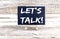 LET`S TALK text on the Miniature chalkboard on wooden background