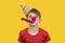 Lets celebrate! Boy in festive hat and clown nose on yellow background. Childrens party