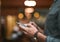 Lets invite some people. an unrecognizable man browsing on a cellphone while standing inside of a beer brewery during