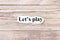 Lets play of the word on paper. concept. Words of lets play on a wooden background