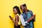 Lets see your secrets. Portrait of a young afro american couple standing back to back using mobile phones isolated over yellow bac