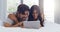 Lets spend the entire day in bed watching shows. Shot of a young attractive couple using a tablet together in the