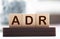Letter block in word ADR Abbreviation of adverse drug reaction on wood background