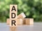 Letter block in word ADR Abbreviation of adverse drug reaction on wood background