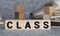 Letter block in word CLASS on wood background