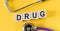 Letter block in word drug on yellow background with stethoscope