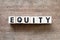 Letter block in word equity on wood background