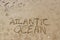 Lettering Atlantic ocean written on the beach. Writing on the wet sand. Vacation and tourism concept