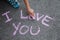 Lettering I love you with pink chalk on gray asphalt