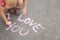 Lettering and love you with pink chalk on gray asphalt