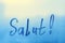 lettering Salut in French is hello in english paint with finger with streaks of water on splashed by rain foggy glass on