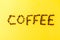 Letters Coffee Beans on yellow vibrant background. Minimalism Food Morning Energy Concept.