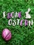 The letters of Happy Easter in German, a pink marbled egg and a decorative little bunny on green easter grass