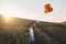 Letters from heaven. a cute little girl attaching a letter to a bunch of balloons while standing in a cornfield.