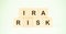 Letters ira and risk with wooden cubes on light green