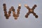 Letters w x of copper coins insulated on a white sheet of paper.