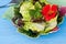 Lettuce and nasturtium flower and leaf salad on decorative bowl on blue table.