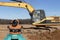 Level with an excavator in the background. Construction level or theodolite. Geodetic instruments and equipment for the