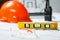 Level meter with blurred Orange hard hat, laptop  with drawings and walkie talkie on a background