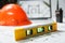 Level meter with blurred Orange hard hat, laptop  with drawings and walkie talkie on a background