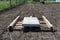 Leveling the chernozem in the yard with a pallet weighted with a concrete cube, preparing for sowing the lawn.