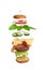 Levitating cheeseburger ingredients: juicy meat cutlet, cheddar cheese, sesame bun, lettuce, white onion rings, slice of tomato,