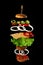 Levitating cheeseburger ingredients: juicy meat cutlet, cheese, sesame bun, lettuce, white onion rings, slice of tomato, cucumber