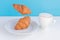Levitating food. Flying croissants for breakfast and a cup of coffee on a blue background. Modern concept food. Levitate