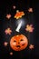 Levitating halloween pumpkin Jack and luminous candle against dark wooden surface, autumn maple leaves flying around.